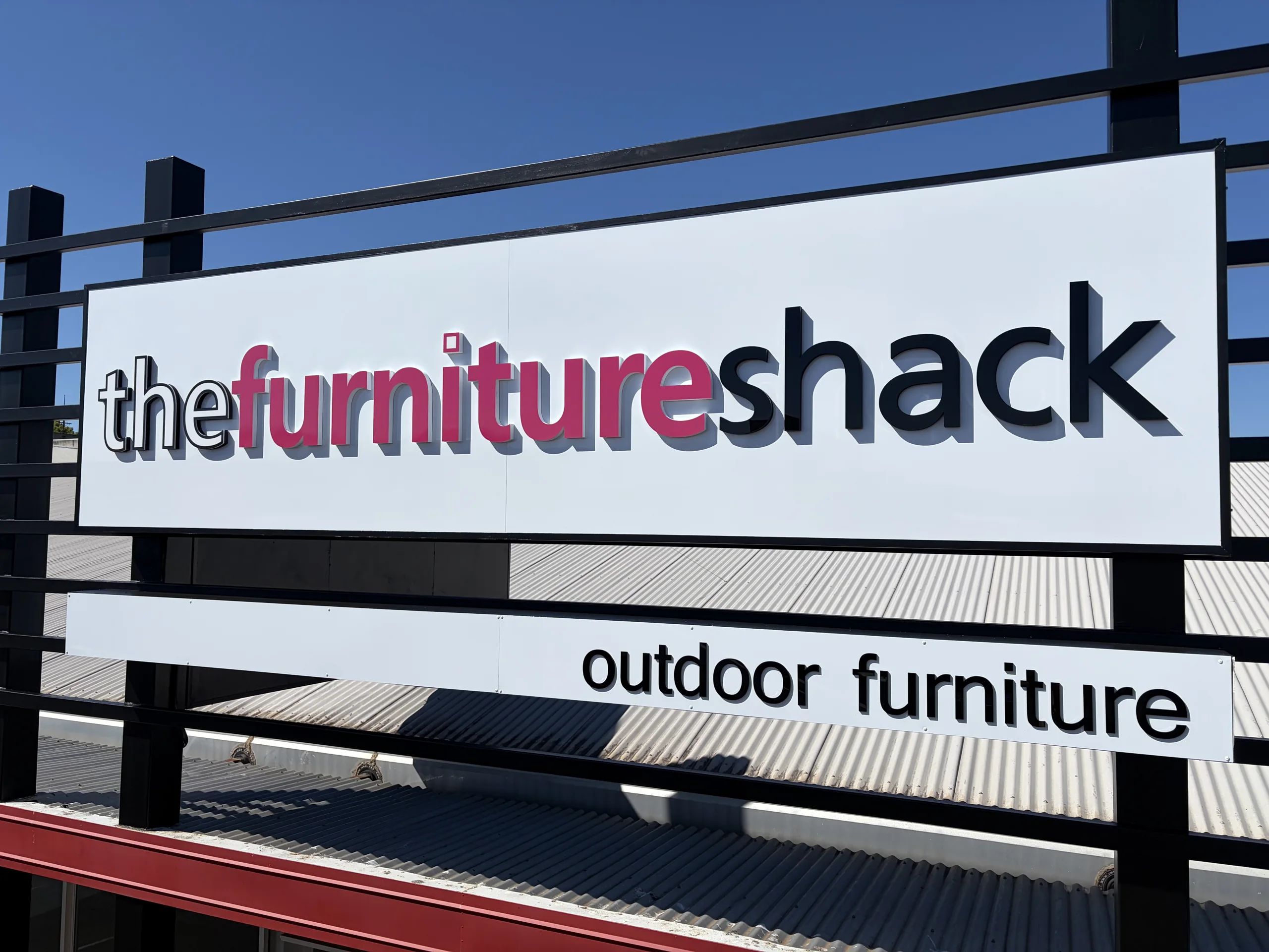 The Furniture Shack outdoor furniture sign on a black steel frame