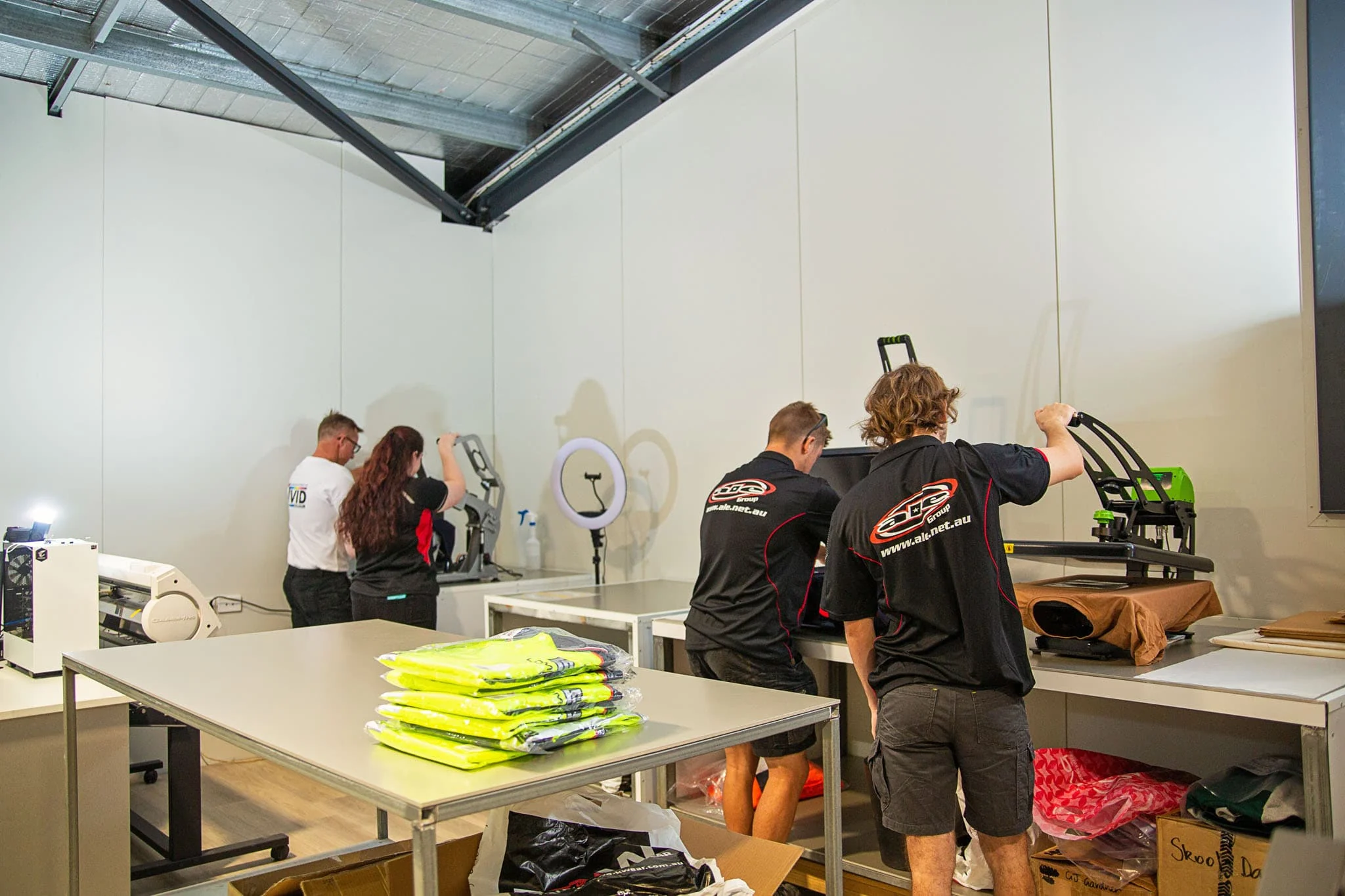 ALE crew heat-pressing branded hi-vis shirts in the clothing workshop