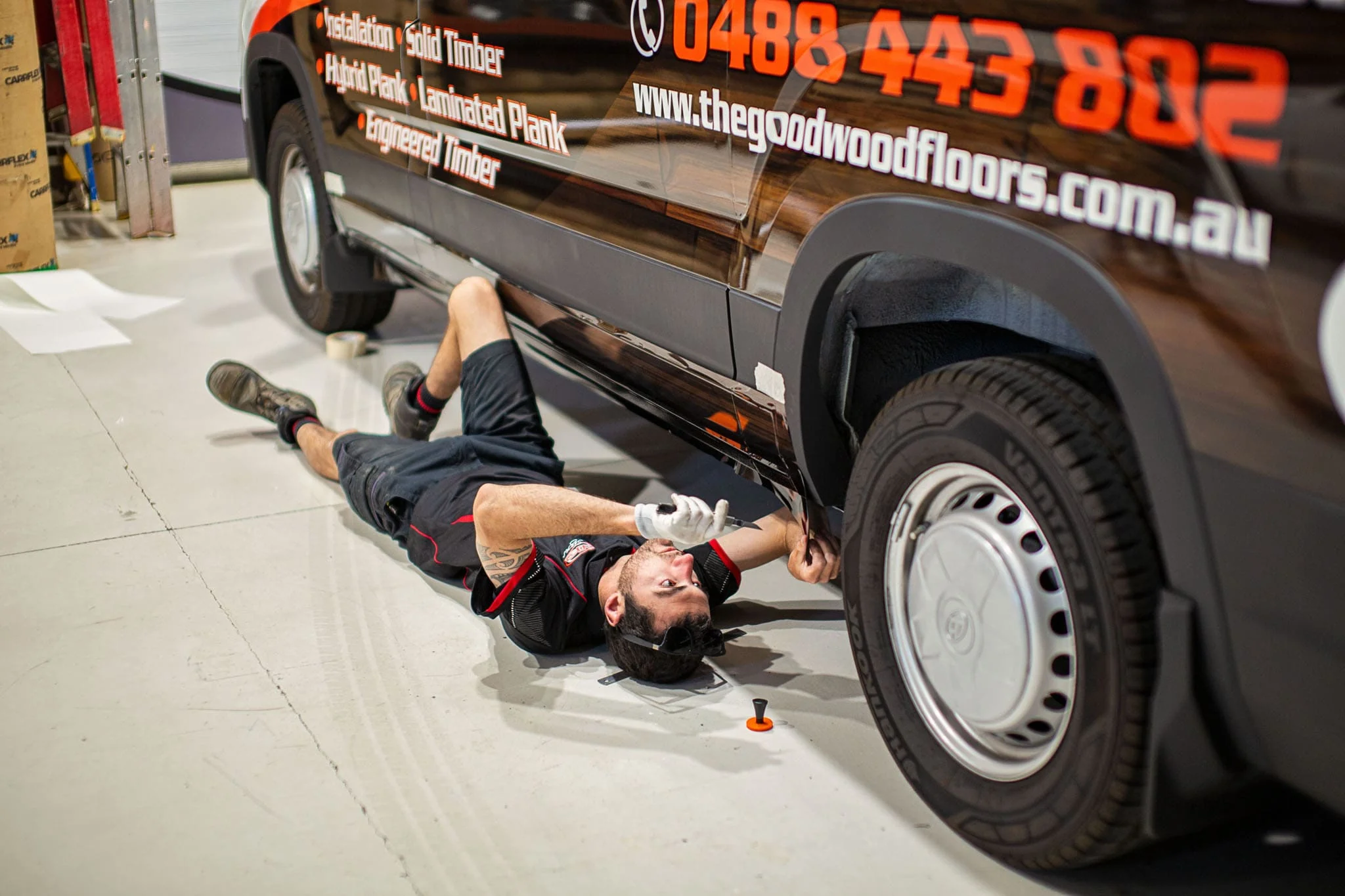 ALE installer lying under a van applying a vehicle wrap